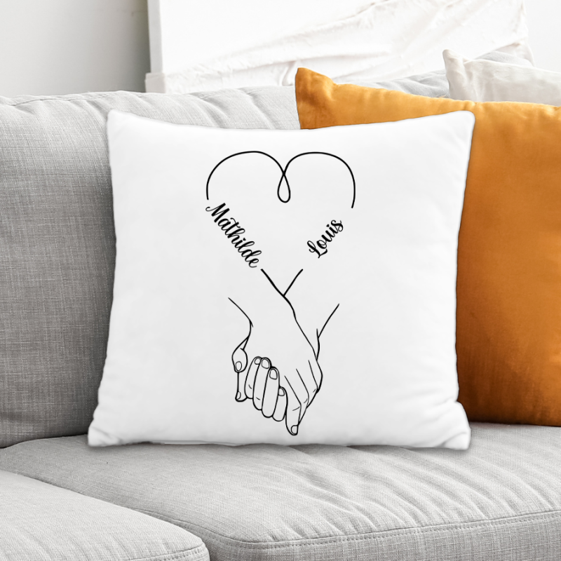 Coussin blanc avec illustration de poignées liées et cœur stylisé, noms Mathilde et Louis en courbes sur les bras. Personnalisé saint valentin.