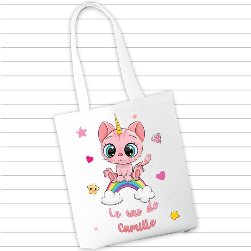 Sac en tissu blanc affichant un dessin mignon d’un chaton rose sur un arc-en-ciel, textes “Le sac de Camille”.
